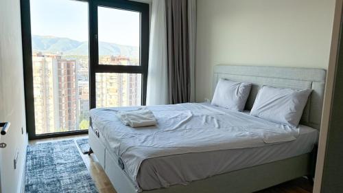 a bed in a room with a large window at City View 1BR - Central Skopje - Free Parking in Skopje