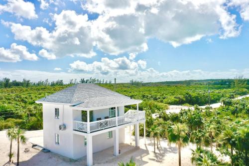 ein weißes Haus am Strand mit Palmen in der Unterkunft Simple Life Cottage cottage in Governors Harbour