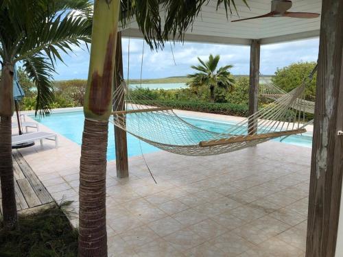 a hammock hanging from a porch next to a pool at Utopia House home in Savannah Sound