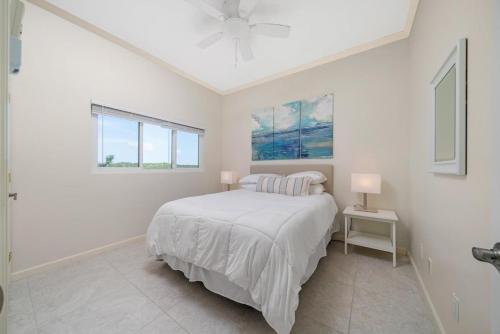 a white bedroom with a bed and two windows at Bella Mer home in Savannah Sound