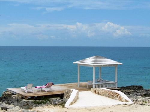 a deck with two chairs and an umbrella on the beach at Coral Point home in Governorʼs Harbour