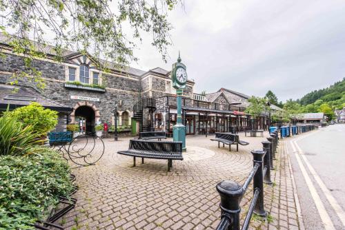 a street with benches and a building with a clock at Alpine Apartments Snowdonia in Betws-y-coed