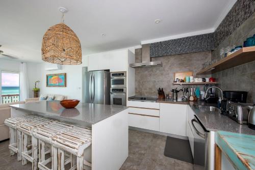 a kitchen with white cabinets and a large island with bar stools at Caribbean SandCastle home in James Cistern