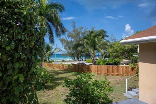 a backyard with a fence and the beach in the background at Winfield Manor home in Governorʼs Harbour