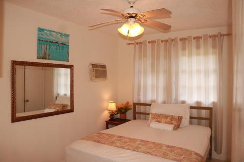 una camera con letto, specchio e ventilatore a soffitto di Ocean Sounds Cottage cottage a Governorʼs Harbour