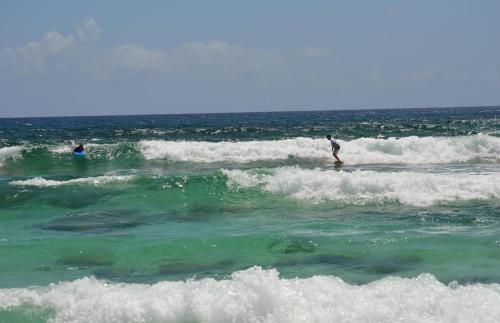 Zwei Menschen reiten Wellen auf Surfbrettern im Ozean in der Unterkunft Palm Bluff cottage in Gregory Town