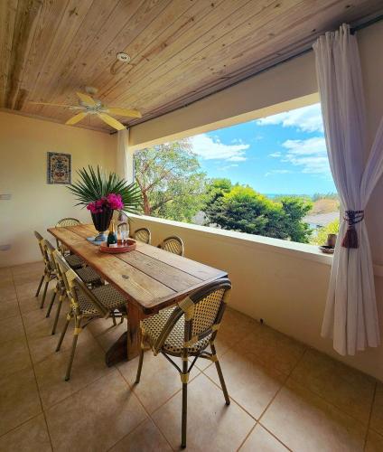a dining room with a table and chairs and a large window at Indigo House home in Governorʼs Harbour