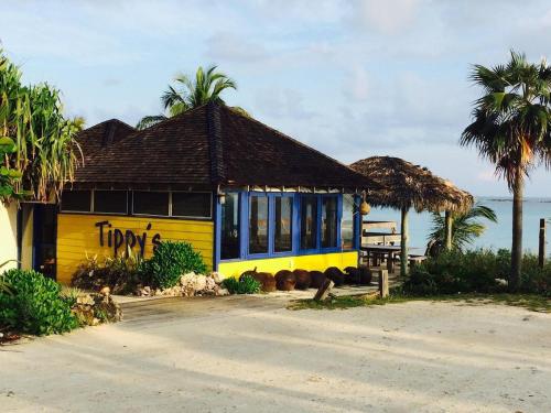a yellow and blue building with palm trees and the ocean at Gumbo Limbo home in Governorʼs Harbour