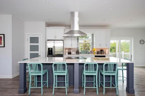 a kitchen with a large island with blue bar stools at Salty Dolphin home in Governorʼs Harbour