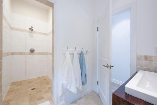 a white bathroom with a sink and a shower at Salty Dolphin home in Governorʼs Harbour