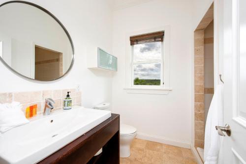 a white bathroom with a sink and a mirror at Salty Dolphin home in Governorʼs Harbour