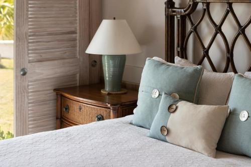 a bed with blue pillows and a lamp on a table at Plage Rose Estate home in South Palmetto Point