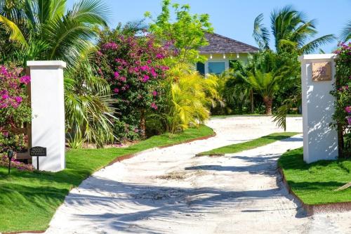 a walkway leading to a house with pink flowers at Wild Orchid home in Governorʼs Harbour