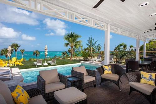an outdoor patio with chairs and a swimming pool at Wild Orchid home in Governorʼs Harbour