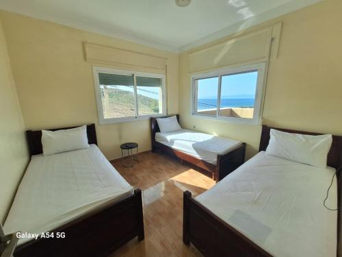 two beds in a room with two windows at Villa Diki beach in Ksar es Sghir