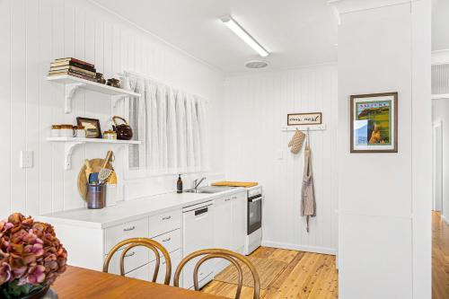 a kitchen with white walls and a table and chairs at Nestle In Narooma - 10 Hillcrest Ave North Narooma in Kianga