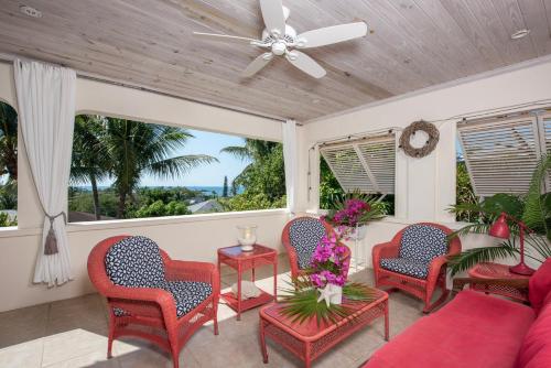 a porch with chairs and a couch and a fan at Indigo 2BR home in Governorʼs Harbour