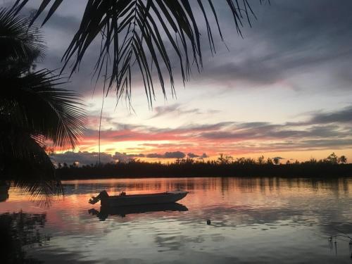 a boat in the water with a sunset in the background at Palm Hill House home in Rock Sound