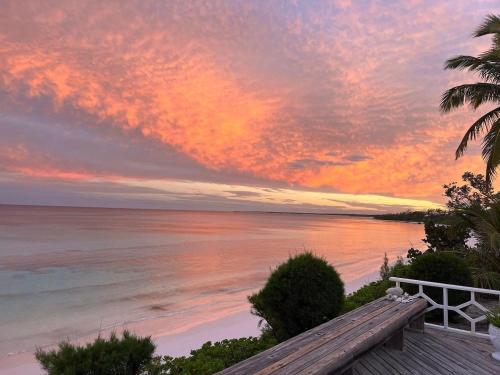 a sunset on the beach with a wooden deck at Palm Hill House home in Rock Sound