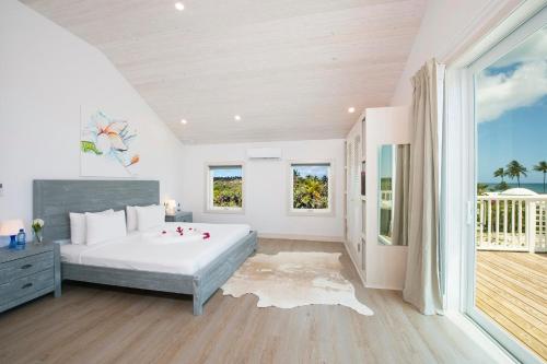 a white bedroom with a large bed and a balcony at See Sea home in Governorʼs Harbour