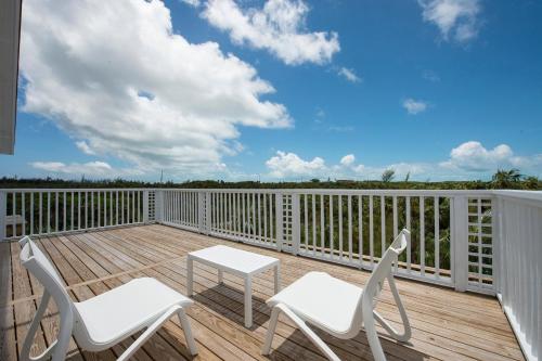 a deck with two chairs and a table on it at See Sea home in Governorʼs Harbour