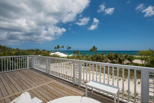 a wooden deck with a bench and the beach at See Sea home in Governorʼs Harbour
