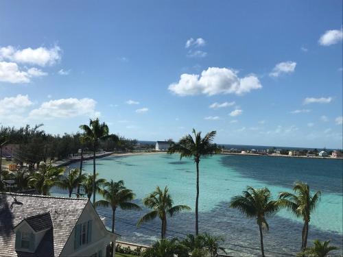 a view of a beach with palm trees and a house at See Sea home in Governorʼs Harbour