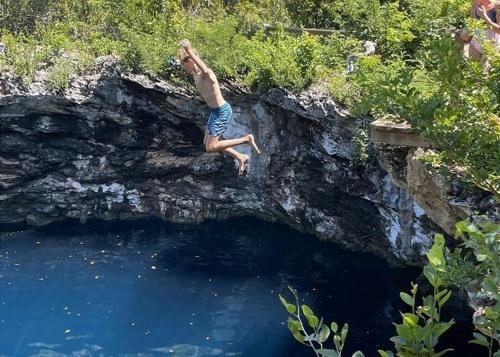 a man jumping off a cliff into a pool of water at Savannah Sunset home in Savannah Sound