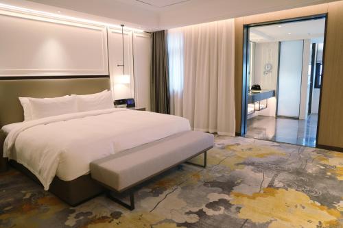 a bedroom with a large white bed and a hallway at Changyuan Xincheng International Hotel in Zhangzhai