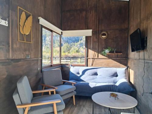 a living room with a couch and two chairs and a table at Cabañas Saiko in Futaleufú