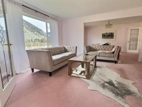 a living room with two couches and a table at Vineyard Vacation Home Hot Tub Sunroom in Keremeos