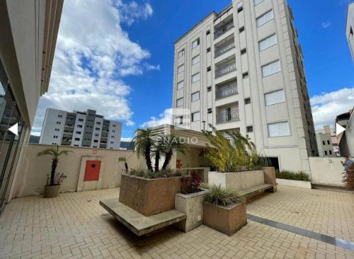 een groot wit gebouw met palmbomen op een binnenplaats bij Apartamento no Centro em Poços de Caldas in Poços de Caldas