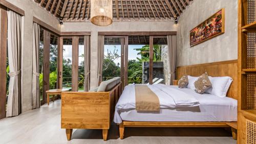 a bedroom with a king sized bed and large windows at Tulip Villa Ubud in Ubud
