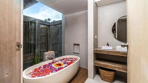a bathroom with a tub covered in confetti at Tulip Villa Ubud in Ubud