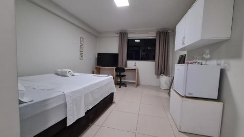 a white room with a bed and a refrigerator at Apart 202 smartTV WIFI AC 100M Cariri Shop in Juazeiro do Norte