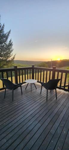 a bench and a table on a deck with the sunset at Shiprock Farm Cottage