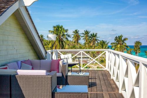 a balcony with chairs and a table and the ocean at Wild Orchid 3 Bedroom home in North Palmetto Point