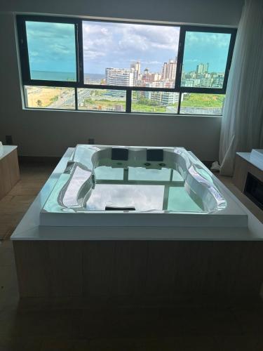 a bathroom with a bath tub in front of a window at Studio beira mar próximo do centro de convenções em Armação in Salvador