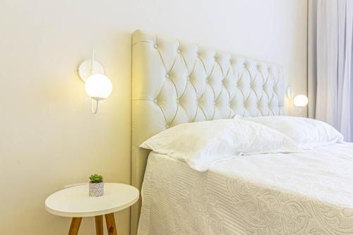 a bedroom with a white bed and a table at Studio no Coração de SP in Sao Paulo