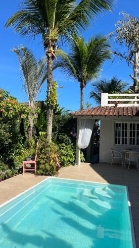 a swimming pool in front of a house with palm trees at GUEST HOUSE Floresta Mar in Angra dos Reis