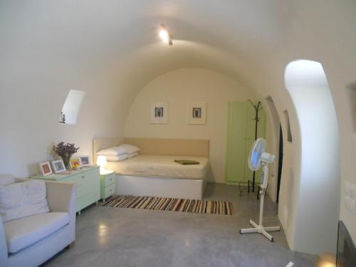 a bedroom with a bed and a couch and a chair at Maira Arch House in Potamós