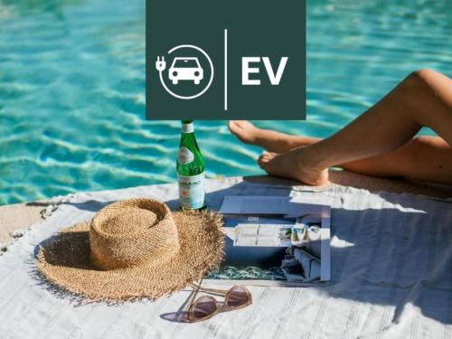 a person sitting next to a pool with a bottle of wine and sunglasses at Noosa Heads Motel in Noosa Heads