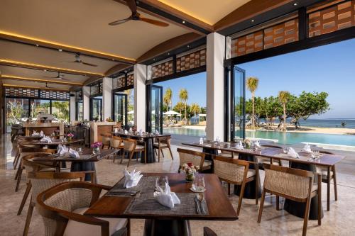 un ristorante con tavoli e sedie con vista sull'oceano di Sumitra Luxury Villas & Resort by Pramana a Sanur