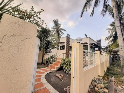 a house with a white fence and palm trees at Rosal House - Beachfront for 12 Pax in Lemery Batangas 