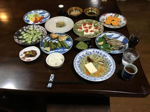 a table with many plates of food on it at Homey Inn Enya in Yufuin