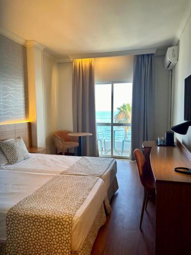 a hotel room with a bed and a desk and a window at Hotel Santa Rosa in Torrox Costa