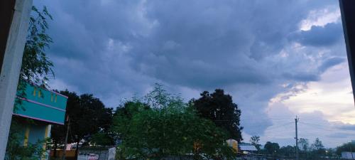 a cloudy sky above a street with a tree at Hotel Jyothi Kumar Royal in Srikalahasti