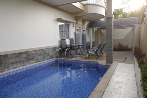a swimming pool with a patio and a house at Diyar Villas Puncak H8/7 in Puncak