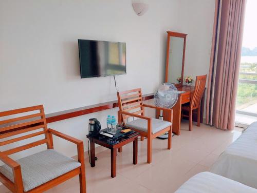 a living room with a tv and chairs and a table at Khách sạn HTC REGINA TUẦN CHÂU in Ha Long