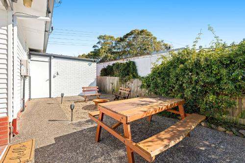 a wooden picnic table and benches in a backyard at Nestle In Narooma - 10 Hillcrest Ave North Narooma in Kianga